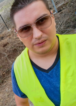 Un ingeniero con lentes oscuros y un chaleco verde brillante en un lugar de construcción