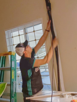 Un hombre sostiene un conjunto de cables que están junto a una pared